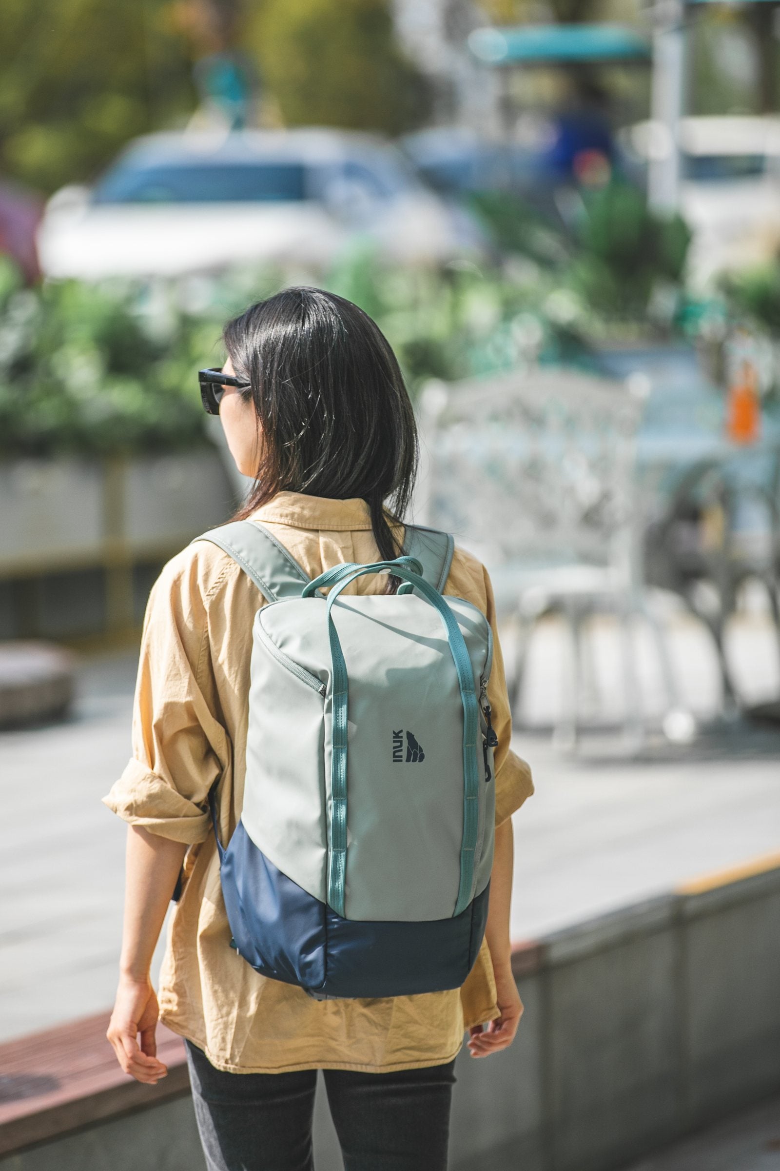 Person wearing the Sage Leaf CRUISER backpack in an everyday city setting
